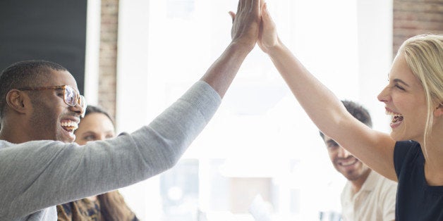 Business people high fiving at meeting in cafe