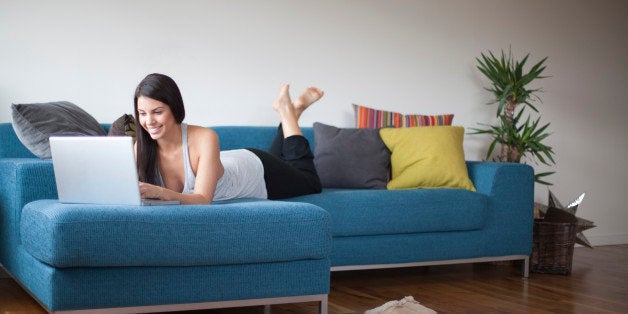 Young woman reclining on couch with laptop computer