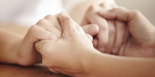 Hands holding each other over a table