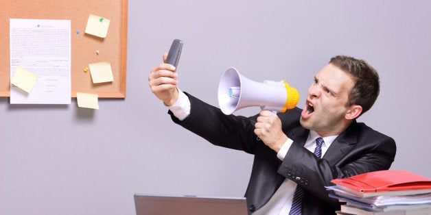 'Angry businessman in an office, shouting on a megaphone'