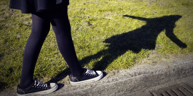 Girls legs walking along the edge of a pavement.