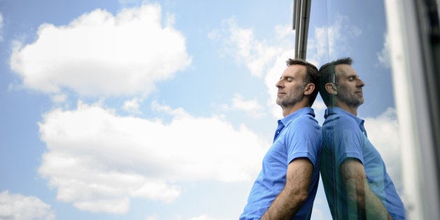 senior man leaning on glass wall