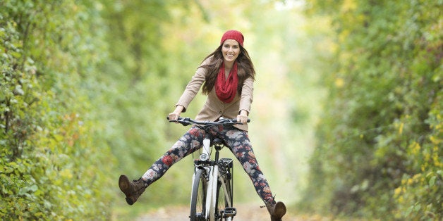 Beautiful woman with a perfect natural expression riding her bicycle through an autumn forest. Nikon D800e.