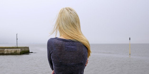 Woman looking out from misty quayside