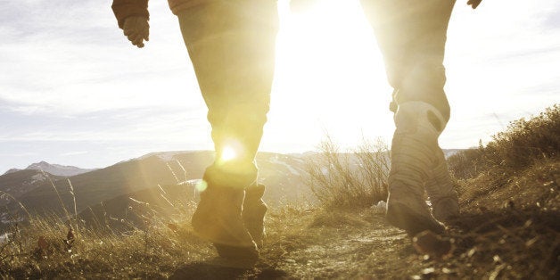 Couple holding hands, walking towards the sun.