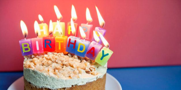 Close-up of candles burning on birthday cake over colored background