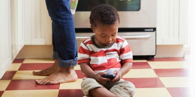 Baby boy sitting on kitchen floor playing