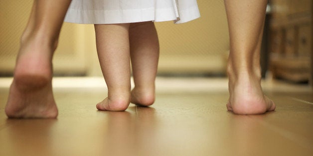 Close up portrait of a mother teaching baby to walk indoors