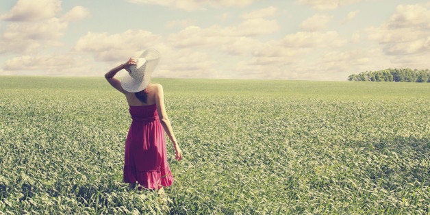 Woman with a big hat on spring field