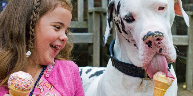 A very happy, natural image of a girl and her pet sharing a treat together.