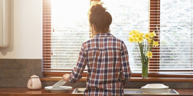 Woman washing up crockery in kitchen.