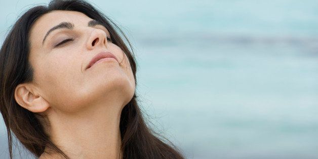 Woman breathing outdoors with head back and eyes closed