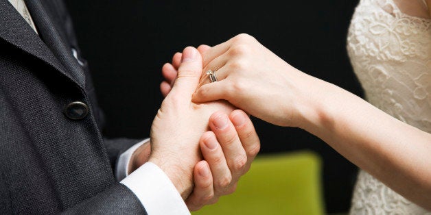 Bride and groom with wedding rings, holding hands, mid section, side view