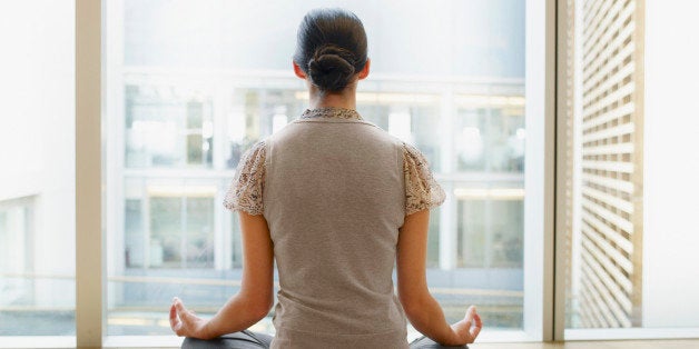 Businesswoman doing yoga in modern office