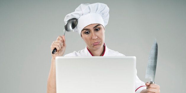 desperate women chef looking at the laptop computer with knife and ladle in her hands