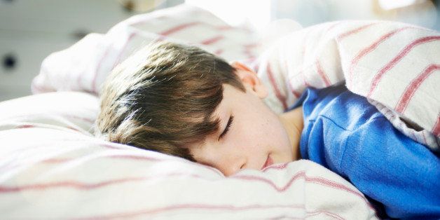young boy fast asleep in bed