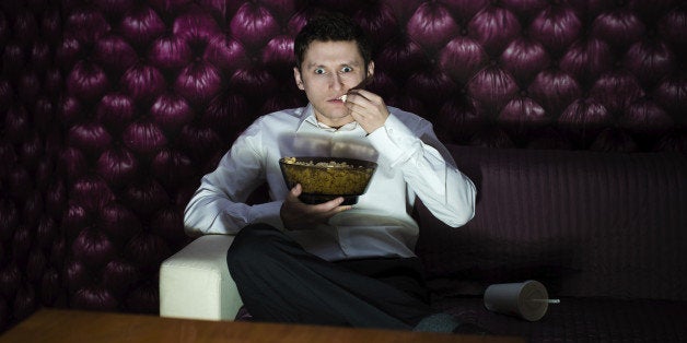 Man watching fascinating program in TV and eating popcorn