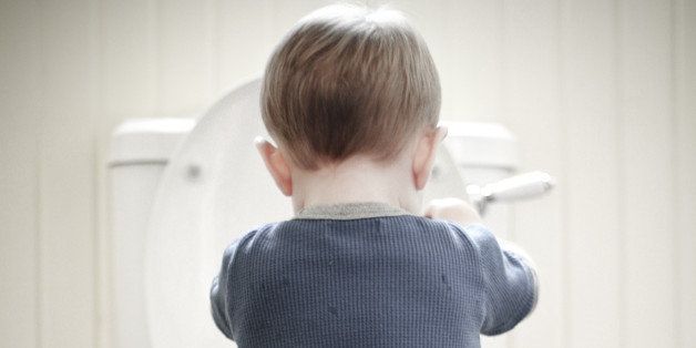 Toddler boy stands in a puddle of water while playing in the toilet