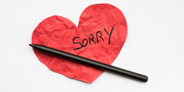 Crumpled red paper heart with pen and the word Sorry written on it.