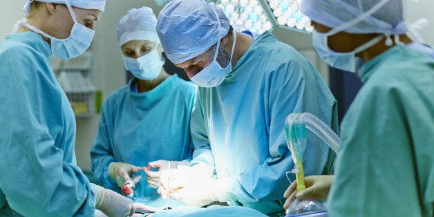 Group of surgeons performing surgery on patient in operating room