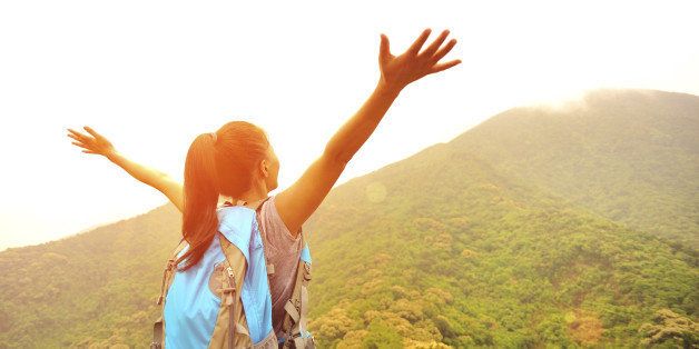 cheering hiking woman open arms at mountain peak