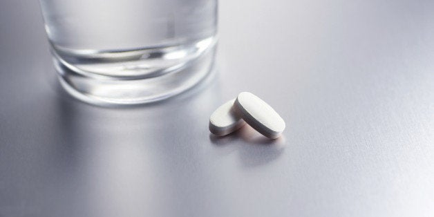 Two pills and a glass of water on table.Similar images -