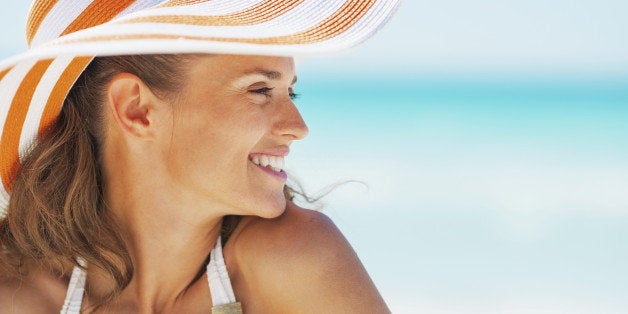 Portrait of happy young woman in swimsuit and beach hat looking on copy space