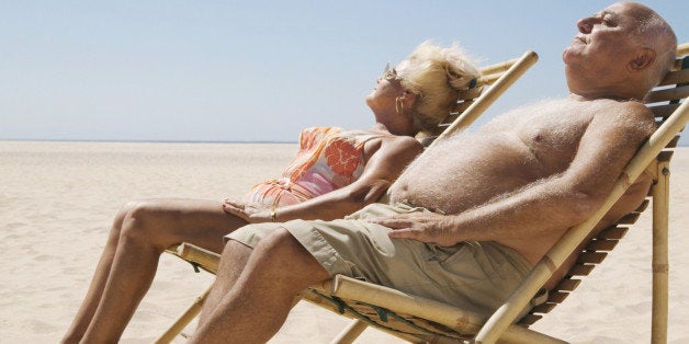 Senior couple sitting in chairs on beach, eyes closed