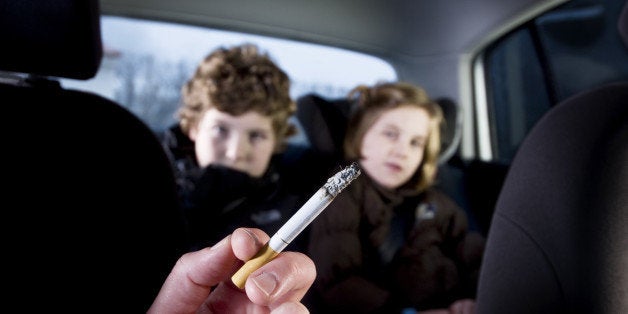 Two young children being subjected to the effects of passive smoking from their mother's cigarette.