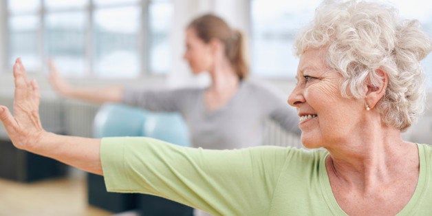 Close-up shot of elderly woman doing stretching workout at yoga class. Women practicing yoga at health club.