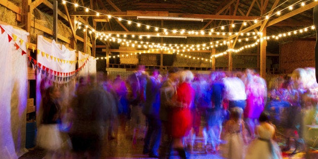 A long slow shutter speed was used to blur the crowd and create a sense of motion at this wedding reception dance party in an old barn in Oregon at night.