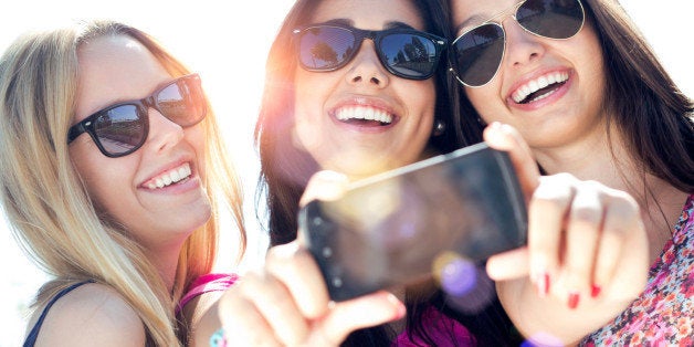 Outdoor portrait of three friends taking photos with a smartphone