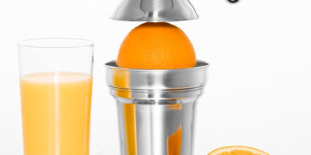 Cut out of a citrus juicer with a glass of orange juice and oranges on a white background