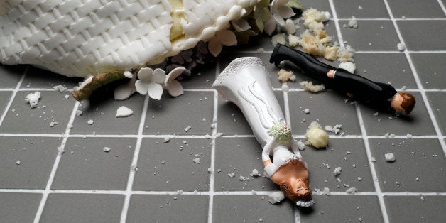 Bride and groom figurines lying at destroyed wedding cake on tiled floor