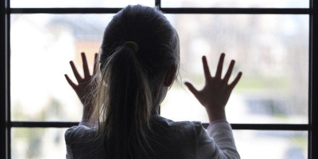 Young girl at window (in partial silhouette) hands pressed against window, pensive or wanting out?