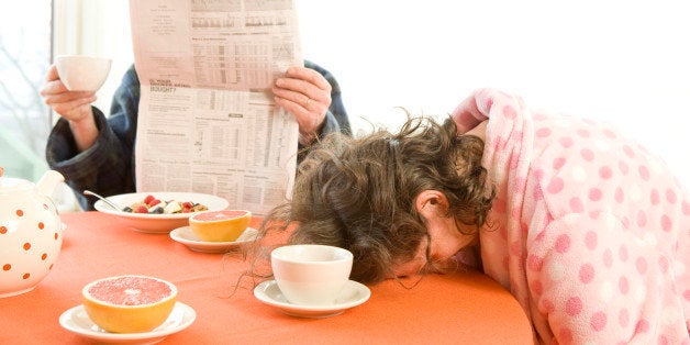 Tired woman with her husband falling asleep during breakfast