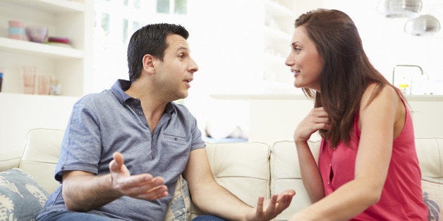 Hispanic Couple Sitting On Sofa Arguing During The Day