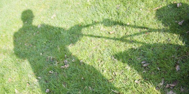 Germany, Petershagen, Shadow of a man mowing lawn