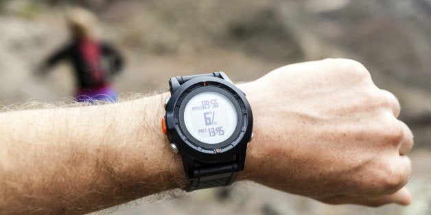 Runner on mountain trail looking at sportwatch, checking performance or heart rate pulse. Sport and fitness outdoors in nature.