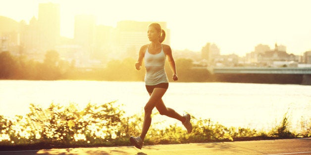 female runner running at sunset in city park. Healthy fitness xwoman jogging outdoors. Montreal skyline in background.Running in city park. Click for more: