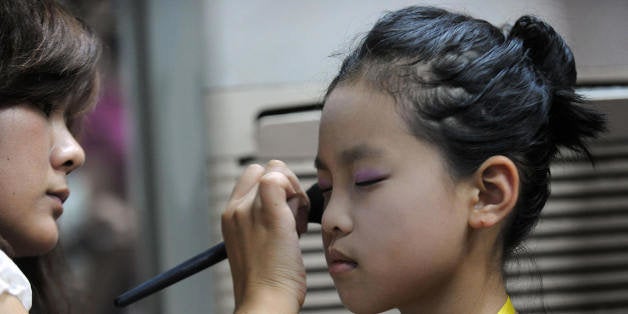 A Chinese mother helps prepare her daughter for a children's beauty and modeling contest in Hefei, in eastern China's Anhui province on July 27, 2009. Beauty pageants were once considered reviled displays of western decadence but have become big business in Communist-ruled China following more than two decades of economic reforms. CHINA OUT AFP PHOTO (Photo credit should read AFP/AFP/Getty Images)