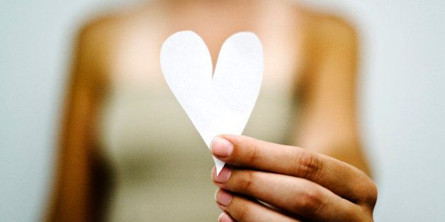 Woman's hand holding out paper heart