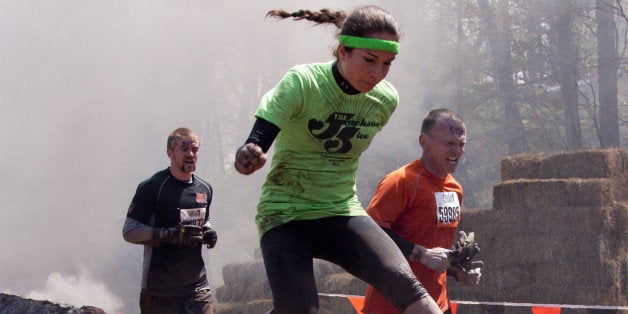 POCONO MANOR, PA - APR 28: A woman runs through the Fire Walker obstacle at Tough Mudder on April 28, 2012 in Pocono Manor, Pennsylvania. The course is designed by British Royal troops.