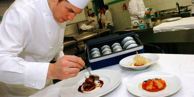 French chef Christophe Larrat prepares roasted quails in a wine sauce from France's Madiran region, left, caponata, a Sicilian dish made of peppers, tomatoes and zucchini, foreground right, and rice pudding with preserved fruit, as part of a menu cooked up by Celebrity chef Alain Ducasse for the international space station, photographed Friday, Dec. 1, 2006 at Toulouse's National Center for Space Studies, southwestern France. Ducasse, who has award-winning restaurants in Paris, New York and Monaco, and chefs from ADF, his consultancy and training department, developed recipes to meet the difficult requirements of dining in space, including zero bacteria. (AP Photo/Remy Gabalda)