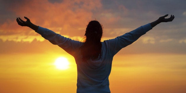 Free woman raising arms to golden sunset summer sky and ocean like praising. Freedom, success and hope concept. Girl relaxing and enjoying peace and serenity on beautiful nature.