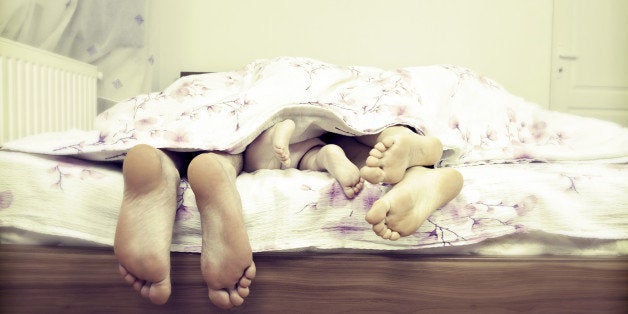 Tree pairs of legs - the happy family in bed: father, mother and baby