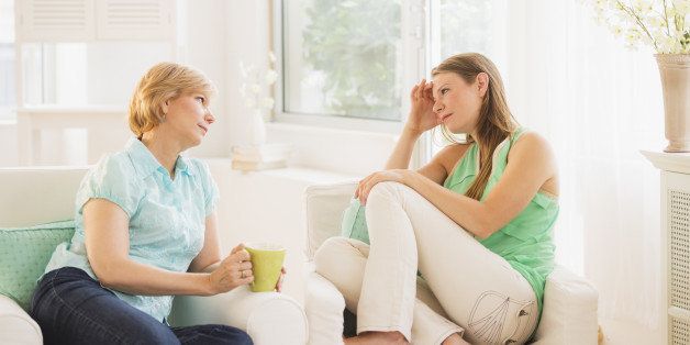 Mother and adult daughter sitting on sofa and talking