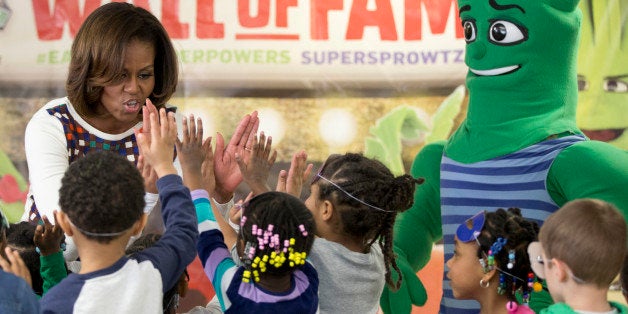 First lady Michelle Obama high-fives children after exercising and dancing with the Super Sprowtz during a visit to La Petite Academy in Bowie, Md., Thursday, Feb. 27, 2014, to show and talk about healthy environments and encouraging healthy habits at preschools as part of her Let's Move! Child Care program. (AP Photo/Carolyn Kaster)