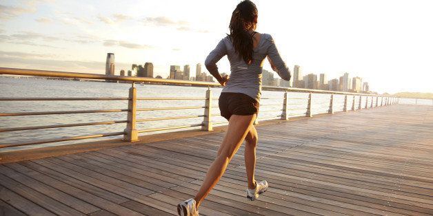 Woman running on pier in front of city skyline