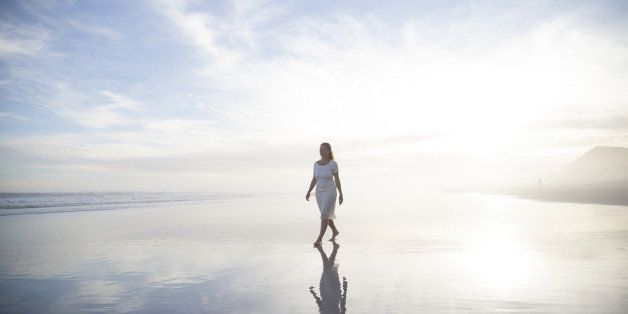 Woman walking alone on a misty beach